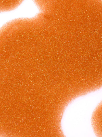 Close up of a glowing orange shimmer texture with fine golden sparkle and a smooth finish from Go-To Skincare Shimmer Party